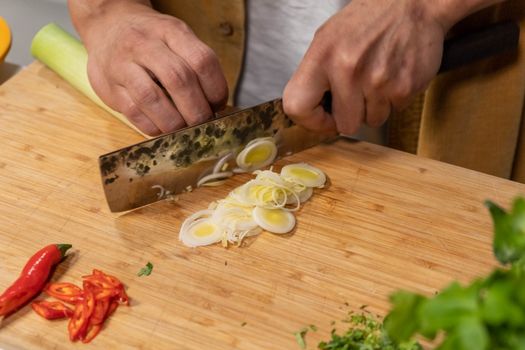 Kom romige doperwtensoep met prei, aardappel en krokante spekjes op een houten tafel
