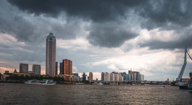 Weer Rotterdam met donkere buienlucht boven skyline en nat verkeer richting Gouda