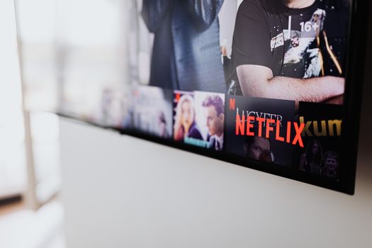 Iemand kijkt thuis op de bank naar Netflix met een lijst van beste series van 2026 in beeld