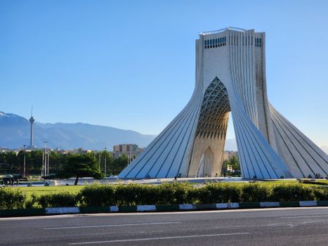 Scherm met iran nieuws en grafiek van olieprijs, met pendelaars bij station Gouda op de achtergrond